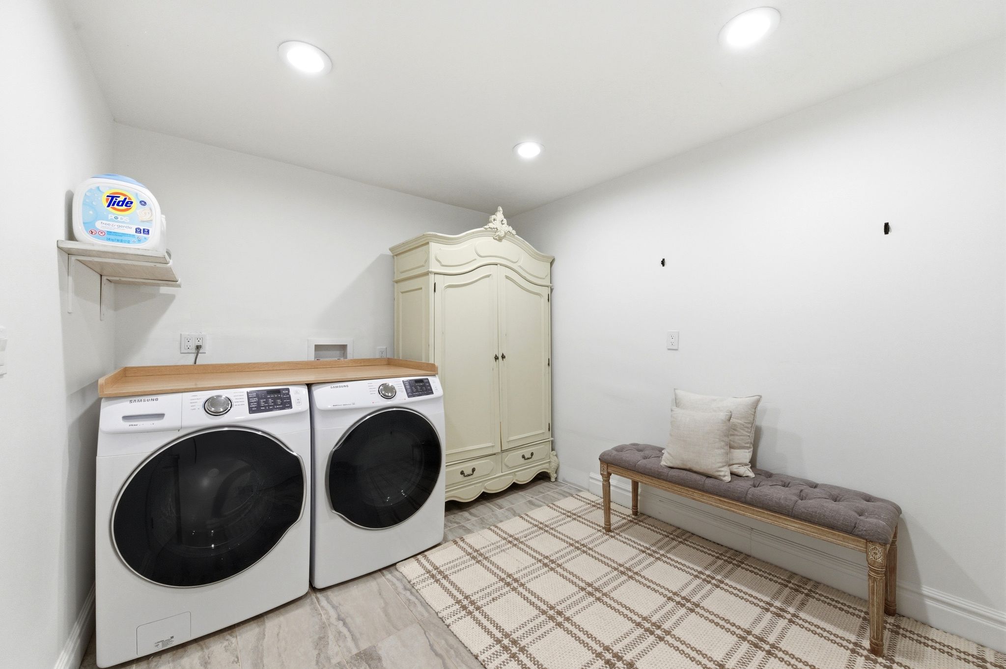Dedicated laundry room with custom armoire and bench